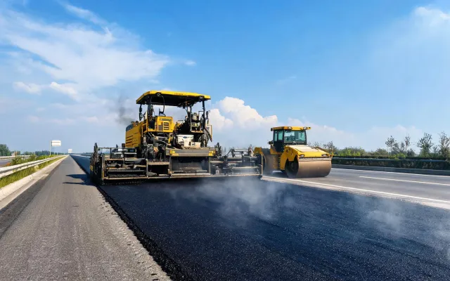 Asphalt paving train with Dynapac rollers following paver